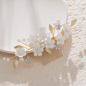 Elegant bridal hair comb with white ceramic flowers, gold leaves, and pearls for weddings