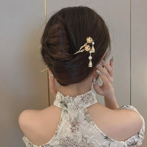 Elegant gold metal hair pin with pearl tassels and floral accents on woman hair