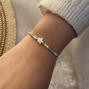 Detail of woven seed bead bracelet with white starfish charm and gold accents