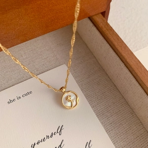 Close-up of golden necklace featuring a white shell pendant with a carved rose detail