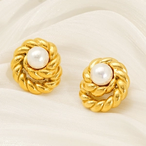 Macro shot of 18K gold twisted knot earrings with pearls on white silk fabric