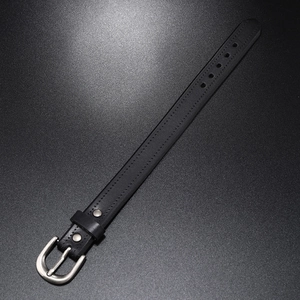 Punk rock black leather bracelet with silver buckle and rivets on dark textured background