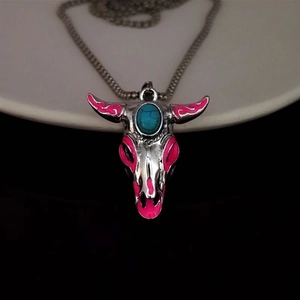 Detail of silver bull skull pendant with blue turquoise stone and pink enamel accents