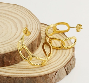 Detailed view of gold chain link hoop earrings on rustic natural wooden coasters