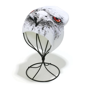 Close-up of white knitted beanie featuring pixelated eagle eyes with red and black details