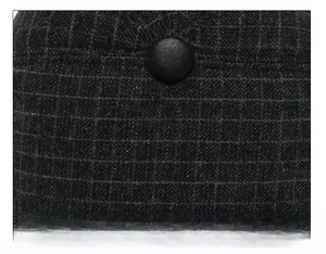 Detailed top view of men's winter flat cap featuring thick black plaid fabric and a leather button
