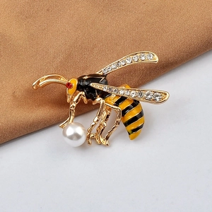 Detailed close-up of a bee brooch with rhinestones, enamel details, and a faux pearl