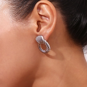 Close-up of model wearing silver twisted textured geometric hoop earrings in stainless steel