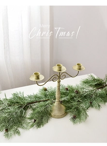 Close-up of vintage cream white three-arm metal candelabra with pine needles and cones