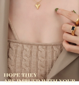 Close-up of gold heart pendant necklace and rings with black square gemstone details