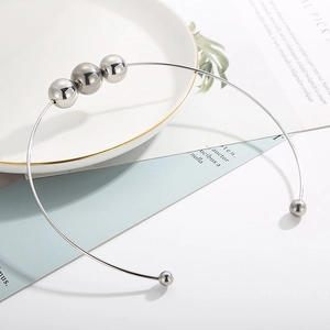 Macro detail of silver stainless steel choker featuring polished hollow metal beads