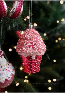 Macro shot of glittery pink cupcake ornament with star sequins on a Christmas tree