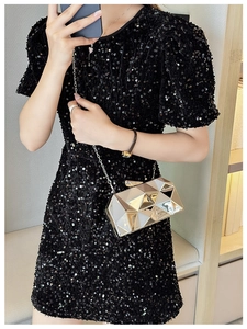 Detail of gold geometric evening clutch bag with metal chain strap on sequined dress