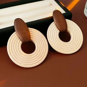Détail de boucles d'oreilles créoles bohèmes en bois et résine avec design rayé