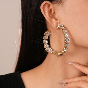 Macro view of large gold-tone C-hoop earring with square-cut sparkling crystals