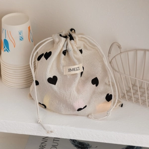 Close-up of champagne heart drawstring pouch with woven logo on satin fabric