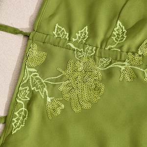 Close-up of green fabric with sequins and leaf embroidery on a summer backless dress