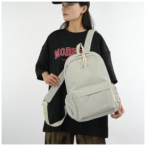 Detailed view of light grey corduroy backpack showing large capacity and side pocket