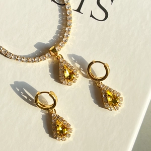 Macro detail of teardrop 18k gold plated necklace and earrings with yellow gemstones