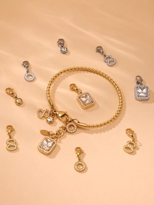 Detail of 18K gold braided cable bracelet with zircon charms on a textured background