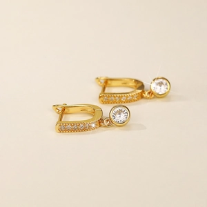Macro detail of gold-plated U-shaped earrings with sparkling cubic zirconia stones
