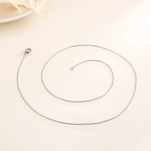 Detail of silver O-chain necklace featuring a secure lobster clasp on a beige background