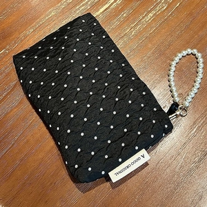Quilted black polka dot makeup bag with elegant pearl handle on a wooden background