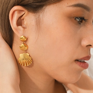 Close-up of model wearing 18K gold stainless steel triple shell tassel drop earrings