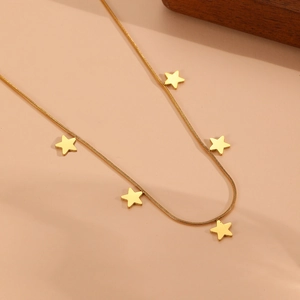 Vue détaillée d'un collier chaîne serpent dorée avec pendentifs étoiles sur fond beige
