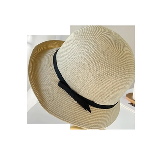Detailed close-up of woven straw texture and elegant black bow ribbon on sun hat