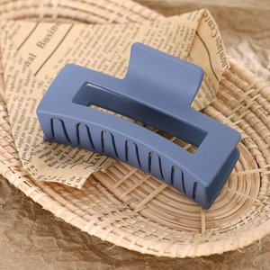 Blue matte square claw clip with hollow design resting on a vintage woven basket