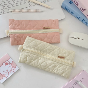 Detailed view of quilted fabric pencil cases in pink and beige with diamond texture