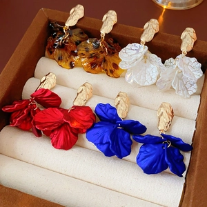Detailed view of four pairs of floral tassel earrings in amber, white, red, and blue colors