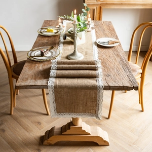 Detail of natural jute table runner with white lace trim on vintage wooden table