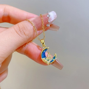 Detailed close-up of golden crescent moon necklace with blue shell and diamond butterfly