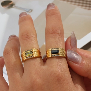 Close-up of 18K gold plated rings with rectangular green and black zircon stones on fingers