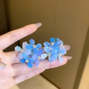 Macro shot of gradient acrylic flower earrings with gold stamens and pearl accents