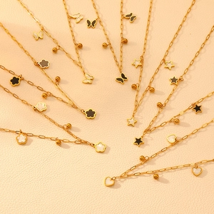 Golden stainless steel necklaces with butterfly and clover pendants on beige leather
