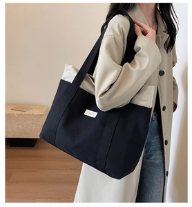 Canvas tote bag with large capacity in black and beige, styled on a female model shoulder
