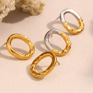 Dettaglio di orecchini a perno ovali irregolari con texture martellata in oro e argento
