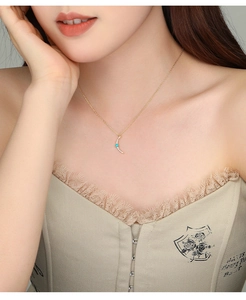 Close-up of a gold-plated crescent moon necklace with turquoise and pavé cubic zirconia