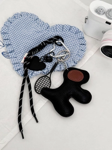 Close-up of black leather dog keychain with woven rope and mini tennis racket charm