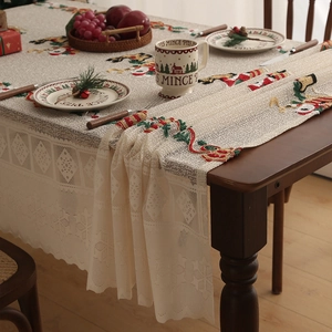 Detailed embroidery of Santa and reindeer on a festive Christmas table runner with lace
