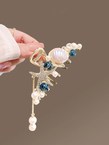Détail du clip à cheveux étoile de mer dorée avec coquillage irisé et perles