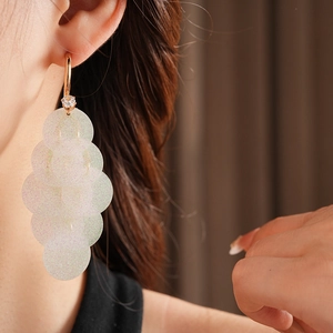 Close-up of C-shaped tassel earrings with white sequins and zircons on a model's ear