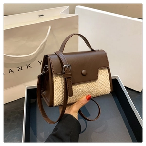 Détail d'un sac à main en cuir PU marron et paille tressée beige avec boucle argentée