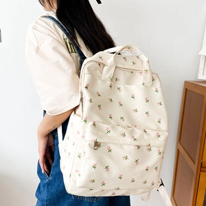 Floral print canvas backpack for women in cream white shown on model from a side-rear angle
