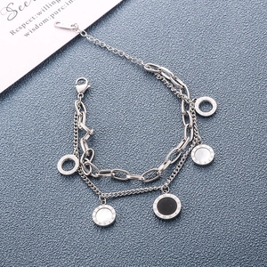 Double-layered silver bracelet with Roman numeral charms and shell inlays on blue background