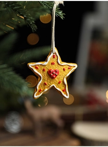 Close-up of a star-shaped gingerbread-style resin ornament with red heart on Christmas tree