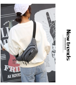Detail of dark grey multi-zipper waist bag with adjustable strap on a street model